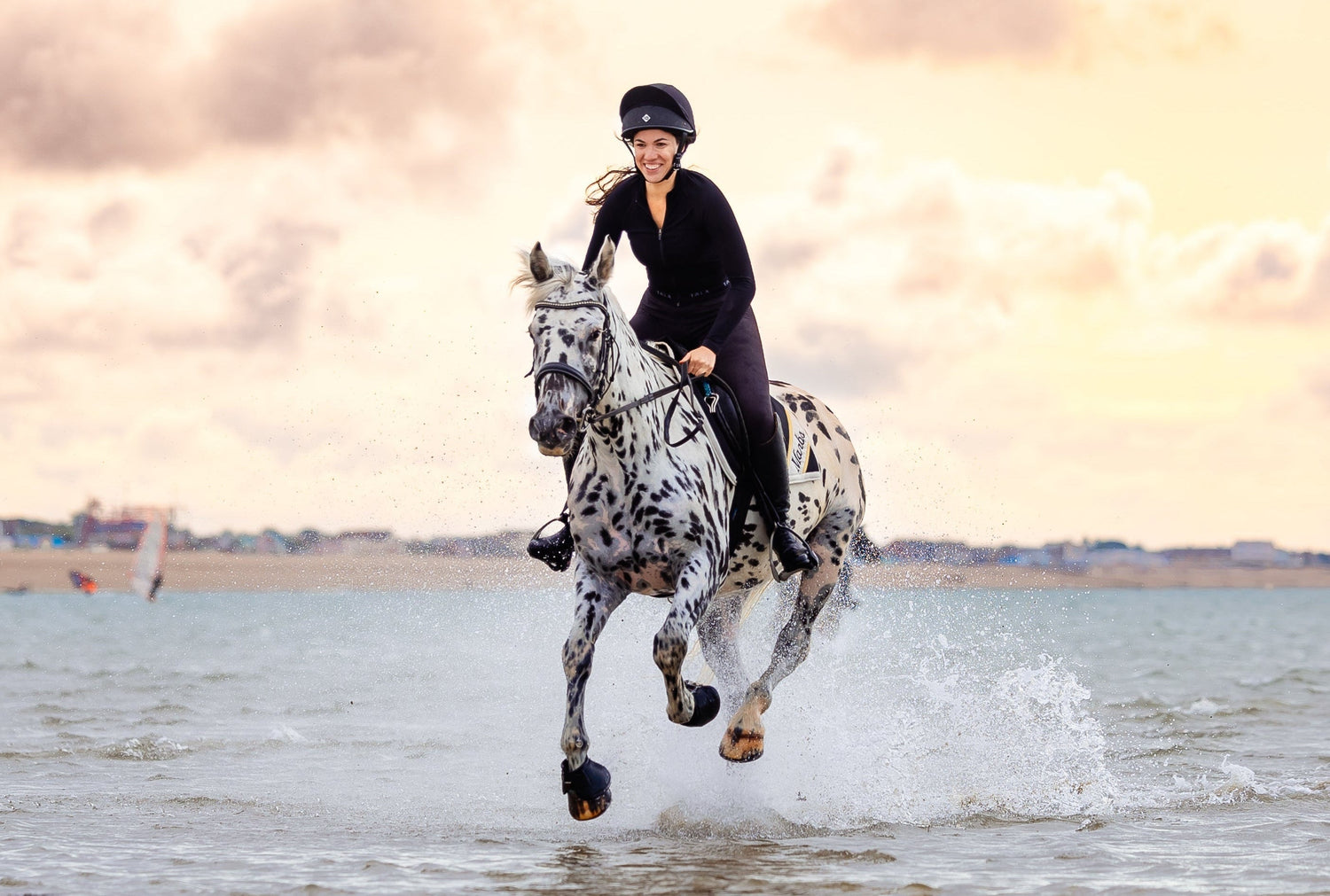 Person riding a horse on a beach with a cloudy sky