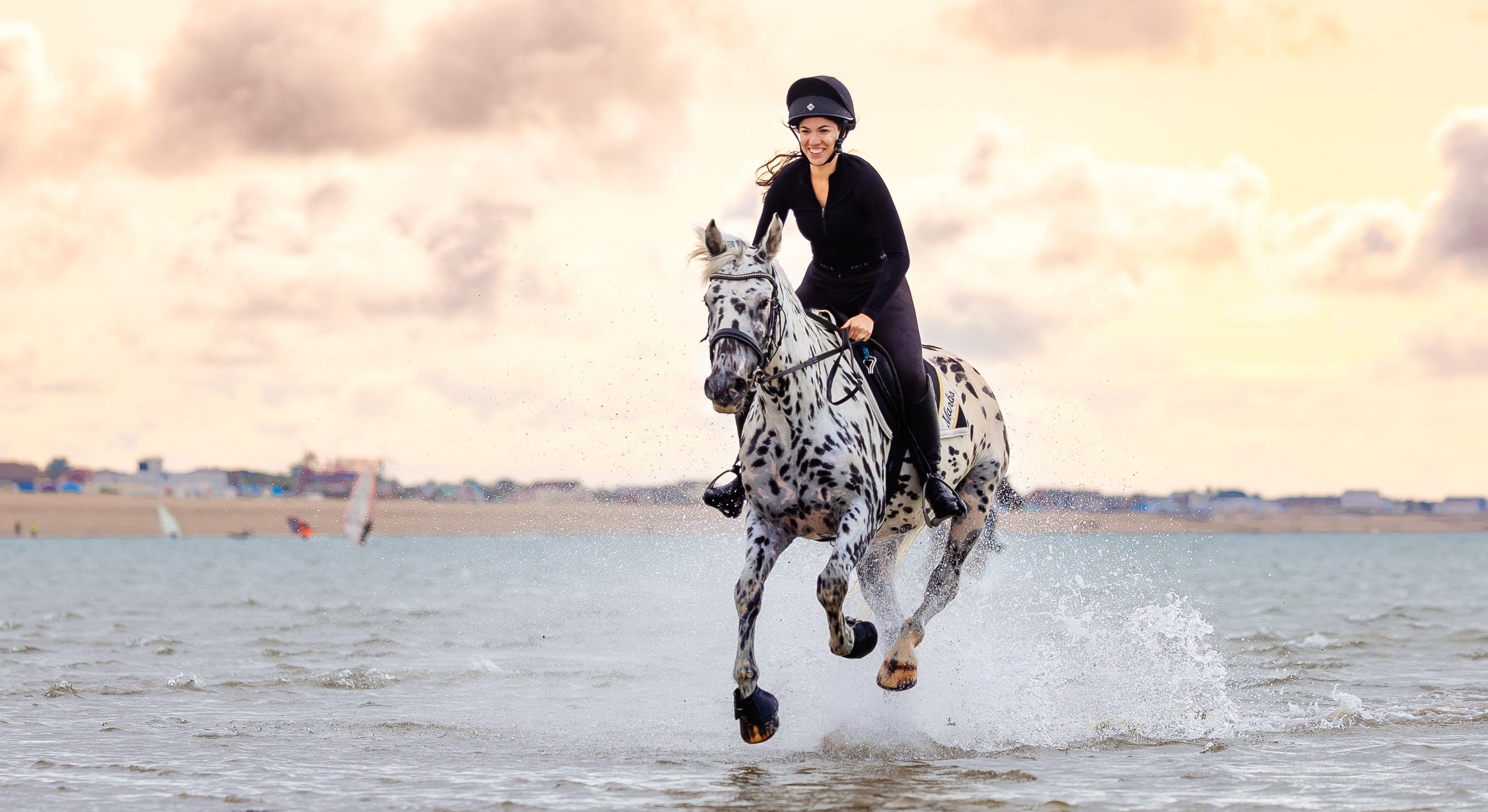 Person riding a horse on a beach with a cloudy sky